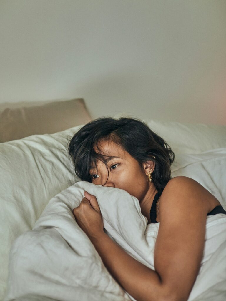 A young woman in bed with period or pregnancy symptoms.