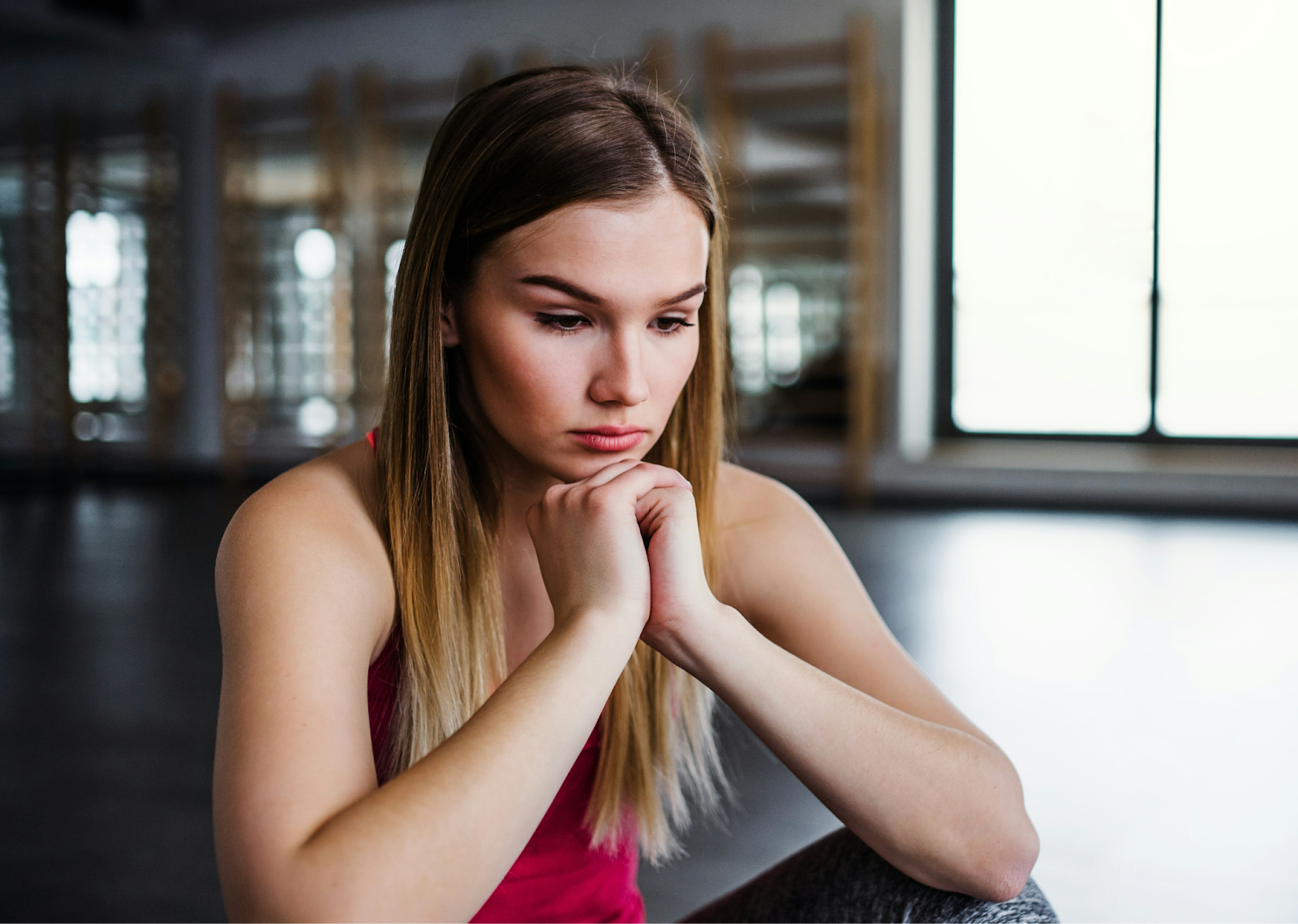 Woman in pink top looking at the ground with her hands folded